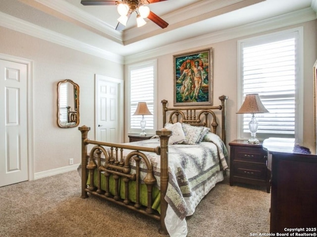 carpeted bedroom with a tray ceiling, ornamental molding, and ceiling fan