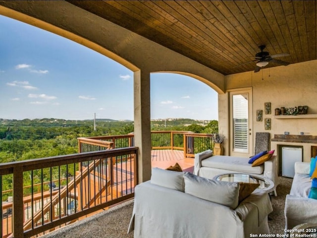 wooden deck with outdoor lounge area and ceiling fan