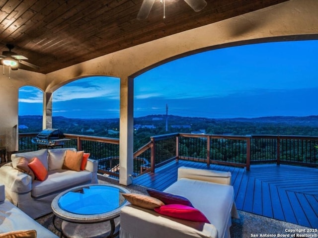 deck at dusk with a mountain view, outdoor lounge area, and ceiling fan