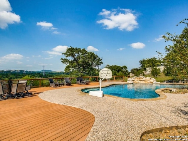 view of swimming pool featuring a patio and a deck