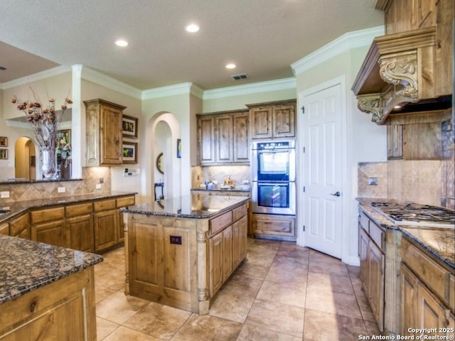 kitchen featuring dark stone countertops, a kitchen island, custom range hood, and appliances with stainless steel finishes