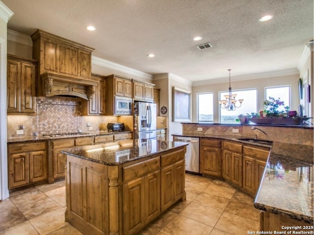 kitchen featuring sink, appliances with stainless steel finishes, hanging light fixtures, backsplash, and a kitchen island