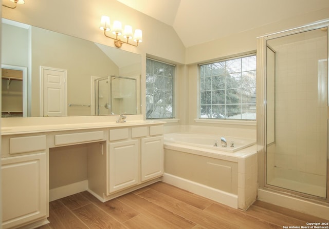 bathroom featuring hardwood / wood-style floors, vaulted ceiling, and plus walk in shower