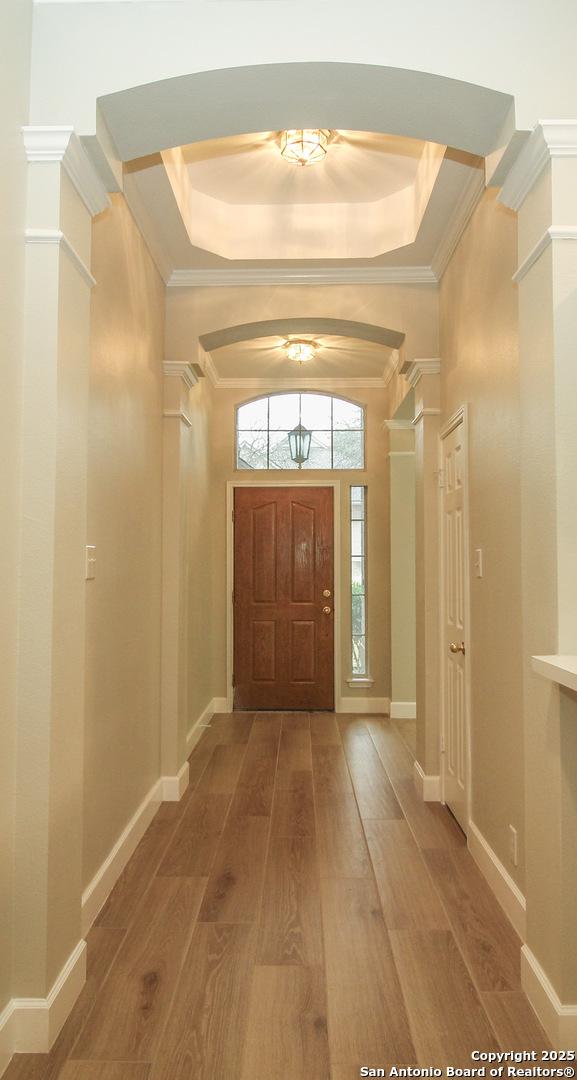 entrance foyer with ornamental molding, wood-type flooring, a tray ceiling, and a high ceiling