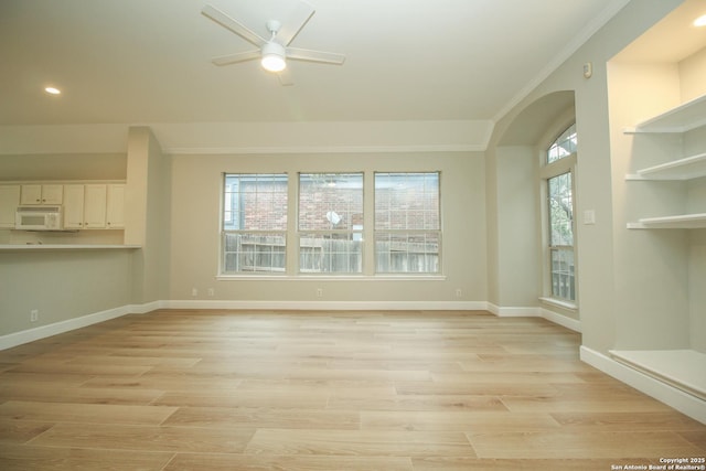 unfurnished living room with ornamental molding, plenty of natural light, ceiling fan, and light hardwood / wood-style flooring