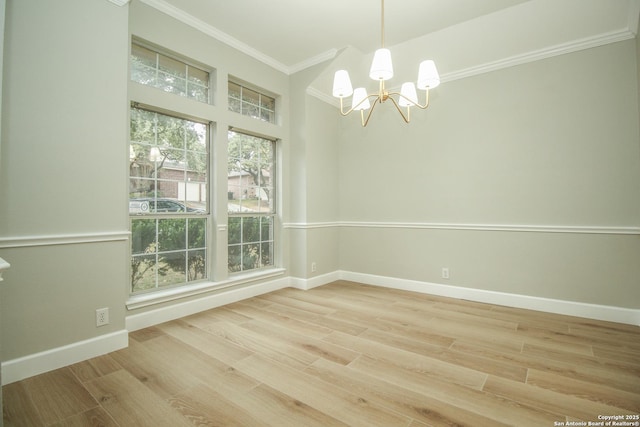 spare room with hardwood / wood-style flooring, ornamental molding, and an inviting chandelier