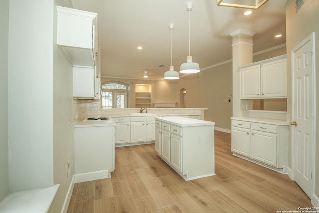 kitchen featuring a kitchen island, white cabinets, hanging light fixtures, kitchen peninsula, and light hardwood / wood-style flooring