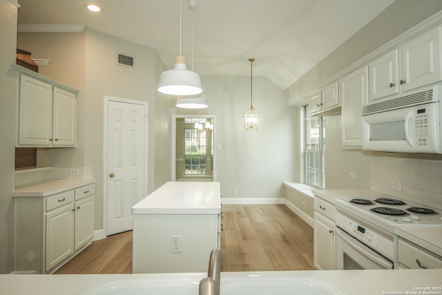 kitchen featuring white appliances, white cabinetry, a center island, decorative light fixtures, and vaulted ceiling