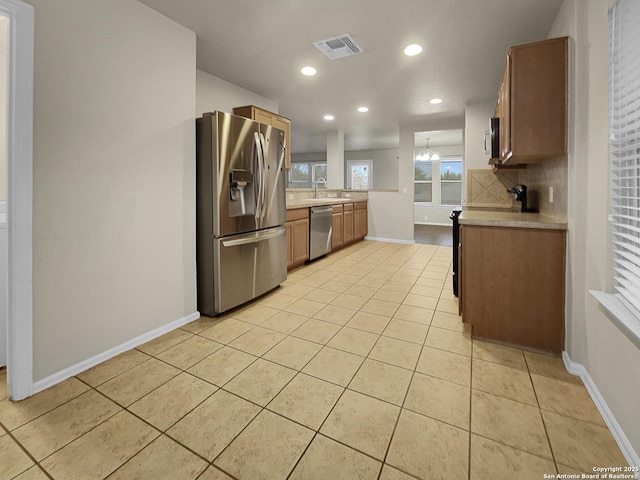 kitchen featuring light tile patterned floors, sink, appliances with stainless steel finishes, backsplash, and kitchen peninsula