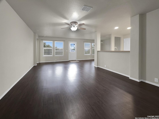 unfurnished living room with ceiling fan, a healthy amount of sunlight, and dark hardwood / wood-style flooring