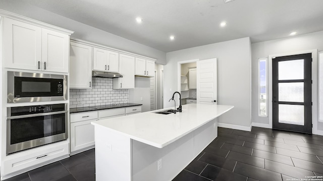 kitchen with built in microwave, stainless steel oven, white cabinetry, and sink