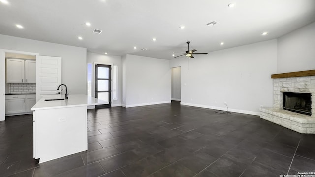 unfurnished living room with sink, a fireplace, and ceiling fan