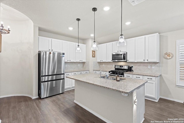 kitchen featuring pendant lighting, an island with sink, white cabinets, light stone counters, and stainless steel appliances