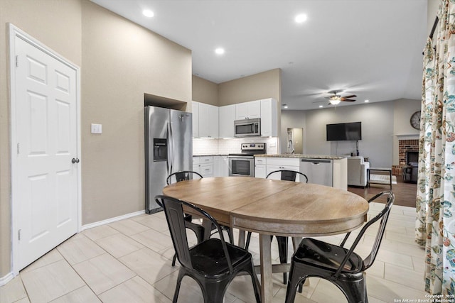 dining space featuring sink, a fireplace, and ceiling fan