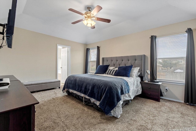 bedroom with vaulted ceiling, light carpet, ceiling fan, and ensuite bath