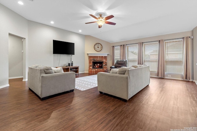 living room featuring dark wood-type flooring, ceiling fan, lofted ceiling, and a brick fireplace