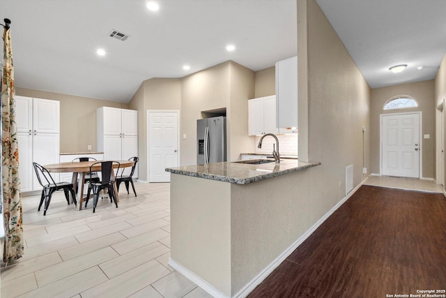 kitchen featuring sink, light hardwood / wood-style flooring, stone counters, white cabinets, and stainless steel fridge with ice dispenser