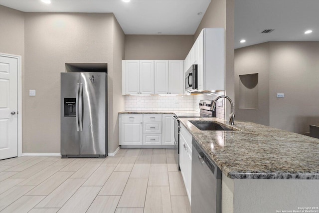 kitchen featuring sink, stainless steel appliances, white cabinets, decorative backsplash, and dark stone counters