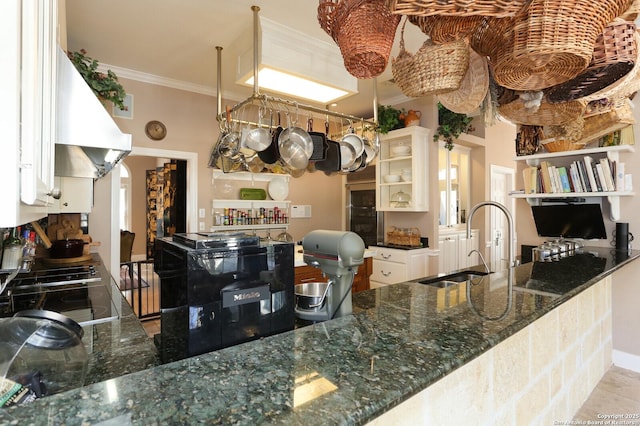 kitchen featuring extractor fan, sink, dark stone counters, ornamental molding, and kitchen peninsula