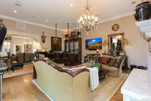 living room featuring an inviting chandelier, hardwood / wood-style flooring, ornamental molding, and bar area