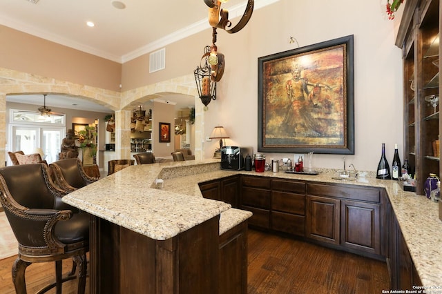 kitchen with dark hardwood / wood-style flooring, crown molding, a kitchen breakfast bar, and kitchen peninsula