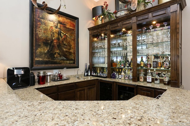 bar with wine cooler, dark brown cabinetry, and sink