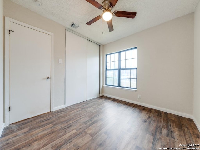 unfurnished bedroom with dark hardwood / wood-style flooring, ceiling fan, a closet, and a textured ceiling