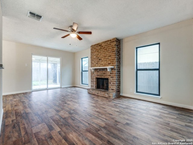 unfurnished living room with a brick fireplace, dark wood-type flooring, and a textured ceiling