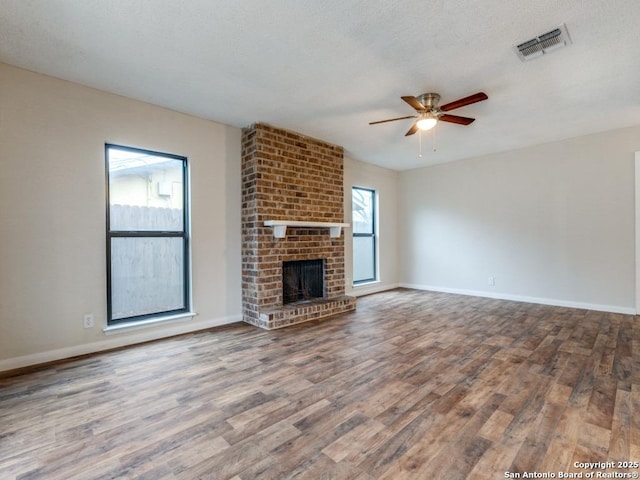 unfurnished living room with hardwood / wood-style flooring, ceiling fan, a fireplace, and a textured ceiling