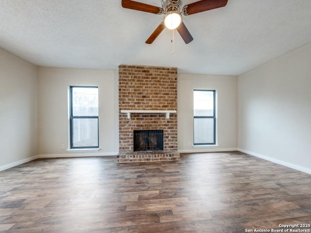 unfurnished living room featuring plenty of natural light, dark wood-type flooring, and a textured ceiling