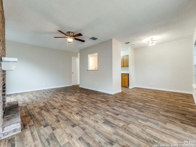 unfurnished living room with a brick fireplace, hardwood / wood-style floors, and a textured ceiling