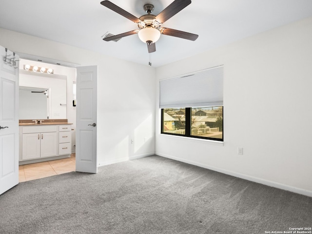 unfurnished bedroom with ceiling fan, ensuite bath, sink, and light carpet