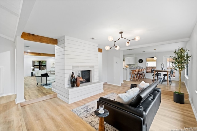 living room with beamed ceiling, a multi sided fireplace, and light wood-type flooring