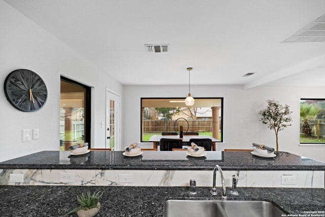 kitchen with decorative light fixtures, sink, and dark stone countertops