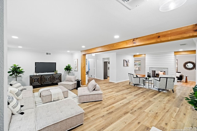 living room with a multi sided fireplace, beamed ceiling, and light wood-type flooring