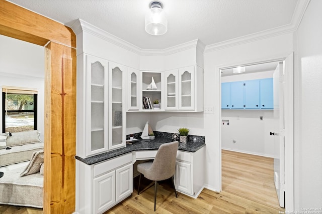 home office with ornamental molding, built in desk, a textured ceiling, and light wood-type flooring