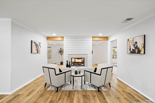 living room featuring a multi sided fireplace, crown molding, and light hardwood / wood-style flooring