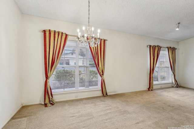 carpeted spare room featuring a notable chandelier and a textured ceiling