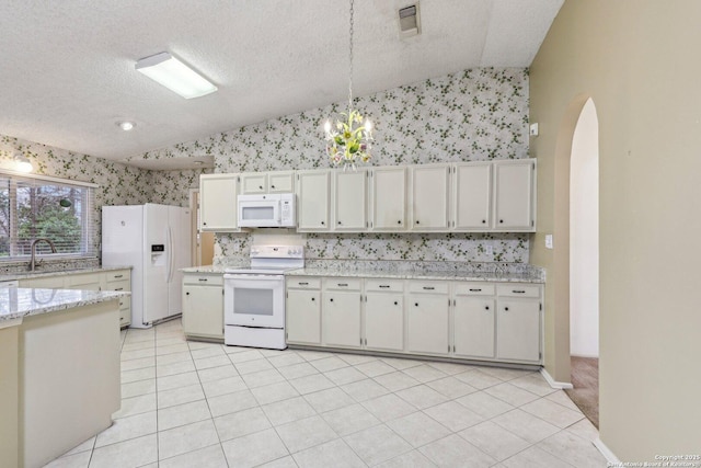 kitchen featuring lofted ceiling, sink, white appliances, white cabinetry, and decorative light fixtures