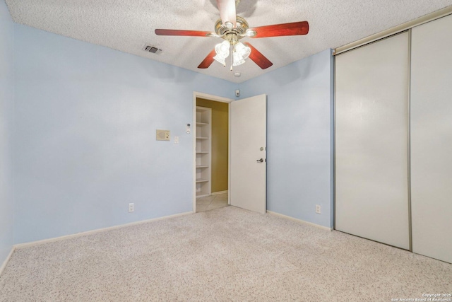 unfurnished bedroom with ceiling fan, a closet, light carpet, and a textured ceiling