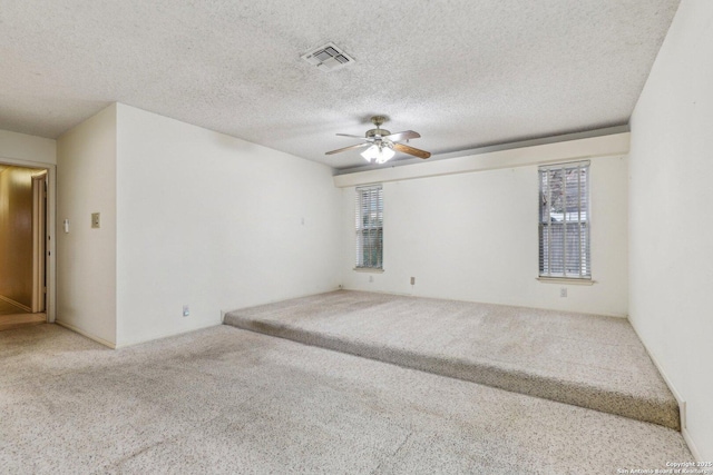 unfurnished room featuring ceiling fan, carpet flooring, a wealth of natural light, and a textured ceiling