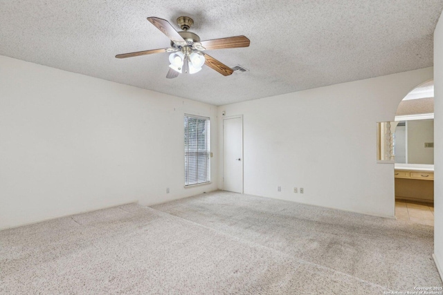 unfurnished room featuring ceiling fan, light colored carpet, and a textured ceiling