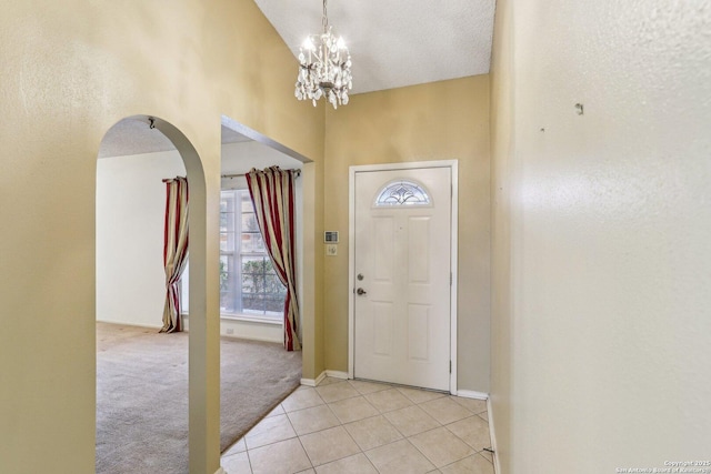 tiled foyer entrance with an inviting chandelier