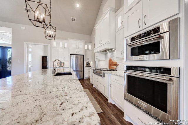 kitchen featuring stainless steel appliances, sink, white cabinets, and decorative light fixtures