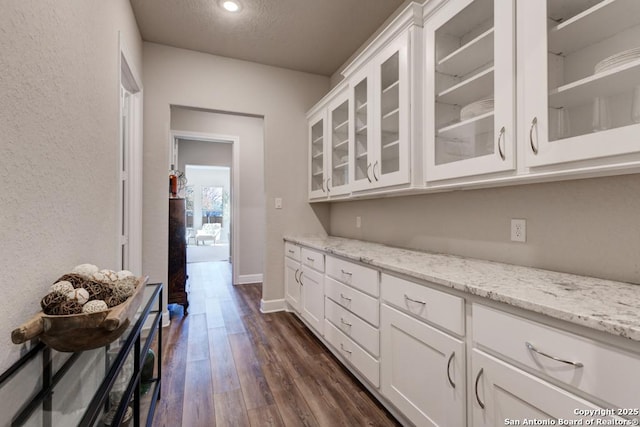 kitchen with light stone counters, dark hardwood / wood-style flooring, and white cabinets