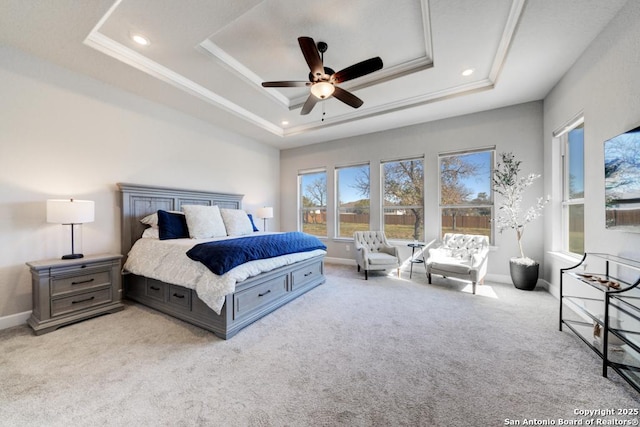 bedroom with crown molding, light colored carpet, ceiling fan, and a tray ceiling