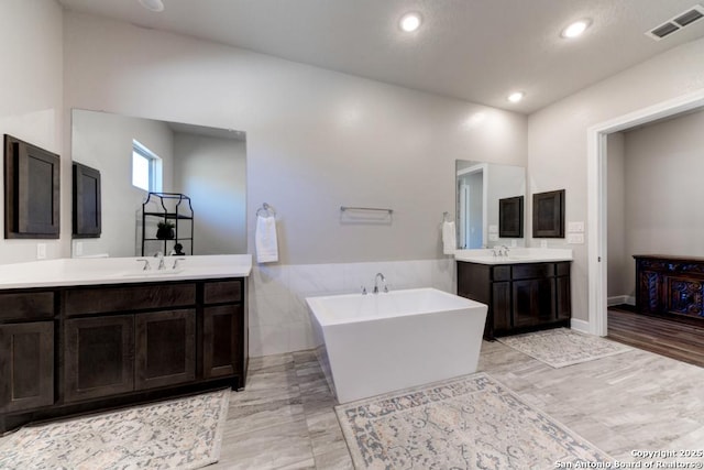 bathroom with vanity, tile walls, and a bathing tub