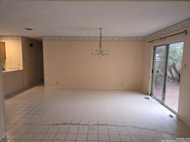 empty room featuring a notable chandelier and a textured ceiling