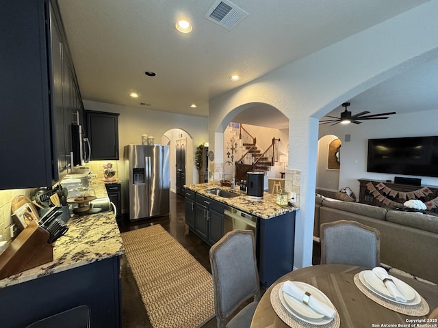 kitchen featuring sink, a breakfast bar, ceiling fan, stainless steel appliances, and light stone counters