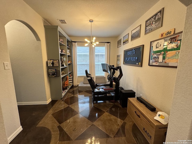 exercise room with a textured ceiling and a notable chandelier